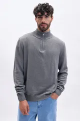 Buzo de tejido de punto en color gris, con cuello alto y cierre frontal parcial. Presenta puños y ruedo acanalados.