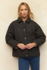 Campera capitoneada negra con botones veteados, bolsillos laterales de solapa y forro de satén con estampado animal print.