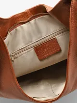 Cartera tipo saco de cuero suave, de diseño amplio y relajado, con asa para llevar al hombro, tiras anudadas a los lados y cierre.