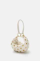 Bolso de hombro de diseño saca multiposición color blanco, decorado con tachas metálicas doradas y aros metálicos que conectan el cuerpo con la manija. Cuenta con cierre de cremallera metálica y bolsillo interior.