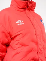 Campera puffer corta de Umbro para el Club Nacional de Football, color azul marino con diseño termosellado. Cuenta con cuello alto, cierre frontal con botones a presión, bolsillos laterales y logo de la marca junto al escudo del club en el pecho.