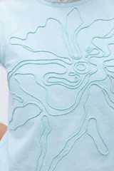Blusa de lino color celeste con bordado en relieve de formas orgánicas y terminaciones desflecadas en las mangas.