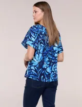 Blusa de poliéster azul con estampado botánico y floral, de silueta holgada y fluido diseño. Cuenta con escote redondo elastizado con frunces y mangas cortas amplias.