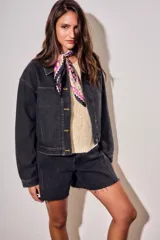 Campera oversize de denim negro, con cuello camisero, cierre frontal con botones y bolsillos ojal.