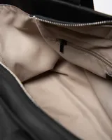 Cartera tipo tote de color negro con asas de hombro decoradas con inscripciones grabadas y detalle de aplique circular con logo en la parte frontal.