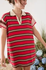 Vestido tipo polo corto tejido de punto, con diseño de rayas horizontales en tonos rojo, marrón y blanco, cuello y escote V en color tostado, y mangas cortas holgadas.