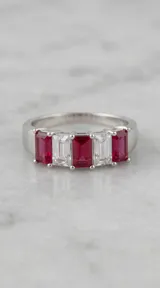 Anillo de plata con diseño de banda compuesto por cristales rectangulares en corte baguette, alternando tonos fucsia y blanco.