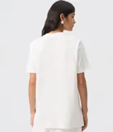 Remera blanca de manga corta y cuello redondo, confeccionada en algodón. Cuenta con una estampa frontal localizada de inspiración bohemia con un marco paisley en tonos rosados y marrones, y el texto "Free Spirit" en el centro.