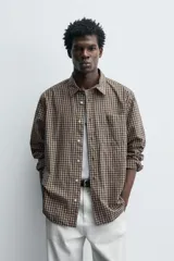 Camisa relaxed fit de algodón con estampado de cuadros en tonos marrón y beige. Cuenta con cuello solapa, manga larga con puño abotonado, bolsillo plastrón en el pecho y cierre frontal de botonadura.