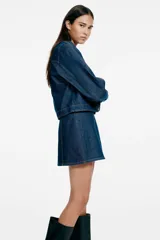Pollera mini evasé de denim azul oscuro, con costuras pespuntadas a contratono y corte ligeramente acampanado.