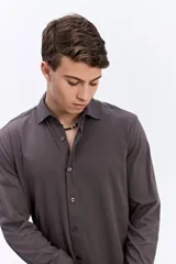 Camisa de manga larga color verde militar, con cuello tradicional y cierre frontal de botones.