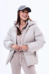 Campera puffer de corte holgado en color beige, con capucha integrada, cierre frontal completo y bolsillos laterales. Presenta un diseño acolchado con acabado mate y puños elásticos.