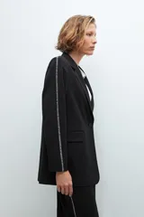 Blazer negro con bordado en contraste a lo largo de las mangas.