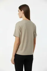 Remera blanca de algodón con cuello redondo y manga corta. Estampado frontal con la palabra "MERCI" en negro con efecto de puntos o tachas.