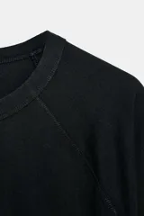 Camiseta de algodón con cuello redondo y mangas largas tipo ranglán. Presenta un corte regular y bajo recto.