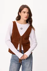 Chaleco de cuero gamuzado color marrón, con escote en V y cierre frontal mediante tiras para anudar.