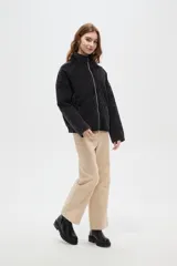 Campera de estilo bomber con diseño capitoneado en forma de rombos, color negro con efecto lavado. Presenta cuello alto, cierre frontal metálico y bolsillos laterales.