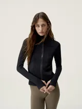 Chaqueta entallada de tejido técnico con cierre frontal completo, cuello alto y mangas largas con aberturas para pulgares. Presenta un diseño de texturas acanaladas verticales.