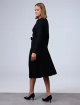Vestido midi negro de tejido de punto, con escote en V cruzado, mangas largas, lazo en la cintura y apliques de perlas en el escote y la cintura.