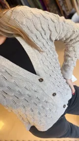 Cárdigan tejido de punto color verde, con diseño de gotas en relieve, escote en V y cierre frontal con botones.