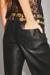 Pantalón de cuero ovino con corte oxford y tiro medio. Presenta diseño de cinco bolsillos, cierre frontal con botón metálico y costuras horizontales a la altura de la rodilla.