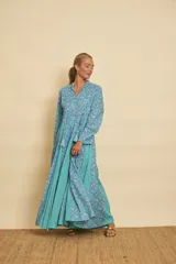 Vestido largo de algodón con estampado de mandalas en tonos celestes y azules, combinado con gajos laterales lisos en color turquesa. Presenta cuello mao con escote en V, mangas largas y silueta amplia y fluida.