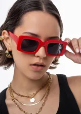Lentes de sol rectangulares con armazón de plástico rojo y lentes oscuros.
