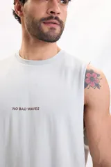 Musculosa verde agua con gran estampado en la espalda de un sol y olas en tono marrón.