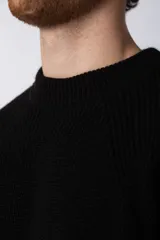 Sweater de tejido grueso con cuello redondo, mangas largas con puños acanalados y corte relajado.