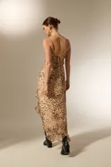Vestido midi de poliéster con estampado animal print, diseño asimétrico con volados en el ruedo, escote en V y breteles finos.