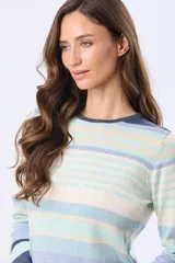 Buzo de tejido fino de algodón con diseño de rayas horizontales en tonos celestes, azules y beige. Presenta cuello redondo, mangas largas y puños en color azul marino.