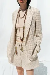 Blazer color crudo con diseño troquelado, cuello solapa, manga larga y bolsillos delanteros de plastrón.