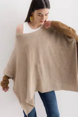 Poncho de tejido de punto con diseño oversize y aberturas laterales. Presenta un acabado con destellos brillantes y cuello redondo amplio.