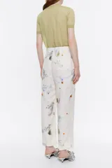 Pantalón tobillero de viscosa con textura y estampado de motivos espaciales. Modelo de corte carrot, con cierre de cremallera frontal y bolsillos laterales. Pinzas en delantero y cinturilla fruncida en el trasero.