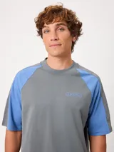 Remera holgada Rusty modelo Isel, de diseño bicolor con cuerpo azul marino y mangas ranglán blancas. Cuenta con cuello redondo ribeteado y pequeño logo bordado en el pecho.