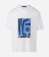 Remera de corte boxy confeccionada en algodón, con cuello redondo y manga corta. Presenta una estampa frontal con diseño artístico abstracto en tonos azules y marrones sobre un fondo claro.