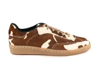 Zapatillas de cuero con textura de pelo, diseño con estampado de manchas tipo vaca en tonos marrón y blanco. Presentan cordones al tono y suela de goma cosida en color caramelo.