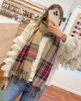 Bufanda rectangular con estampado a cuadros en tonos beige, gris, rosa y amarillo. Tiene flecos en los extremos.