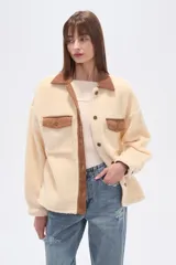 Campera tipo shacket de corderito color crema, con detalles en pana marrón en cuello, solapa de botones y bolsillos frontales. Diseño holgado de manga larga con cierre frontal de botones.