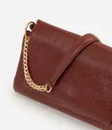 Cartera tipo shoulder bag de tamaño grande, confeccionada en poliuretano con textura de efecto croco. Presenta una solapa frontal con cierre magnético, herrajes en tono dorado claro y una correa de cadena metálica. Incluye un bolsillo interno con cremallera.