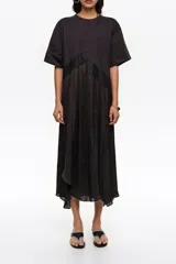 Vestido midi de línea A con vuelo y diseño bimateria, de color negro. Presenta escote redondo, mangas cortas amplias y detalle de encaje superpuesto en la cintura con diseño irregular.