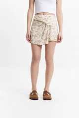 Falda corta tipo pareo con diseño envolvente y nudo frontal. Presenta un estampado marmolado en tonos tierra sobre fondo claro.