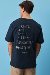 Remera blanca de algodón, de corte holgado y mangas cortas, con pequeño estampado azul en el pecho.