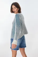 Sweater de punto a rayas verticales blancas y negras, con cuello redondo y mangas largas.