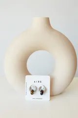 Aros de argolla en acero quirúrgico con dije de piedra natural en tono azul.