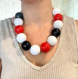 Collar corto con cuentas grandes de resina en colores blanco, negro y rojo.