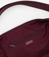 Bolso hobo negro con correa transversal ajustable y cierre en cremallera.