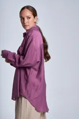 Camisa negra de tela traslúcida con cuello clásico, cierre frontal con botones y dos bolsillos de parche en el pecho.