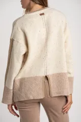 Sweater oversize de lana con diseño color block, combinando un cuerpo en tono crema con motas multicolores y una franja inferior ancha en color visón. Presenta cuello redondo y detalles acanalados en el cuello, puños y ruedo, además de franjas laterales texturizadas en las mangas.