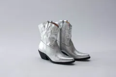 Botas de estilo western (texanas) de caña media, color blanco, confeccionadas en cuero. Presentan bordados decorativos en la caña y puntera cuadrada. Cuentan con cierre lateral y taco de altura media.